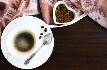 Cup of black coffee with coffee spoon ,brown sugar and vintage napkin on wooden background. Copy space.