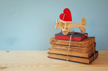 Wooden plane with heart on the stack of old books