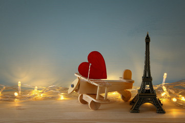 Fototapeta na wymiar Wooden plane with heart next to Eiffel Tower