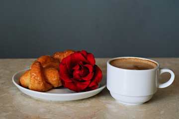 Cup of coffee, croissants and rose on table in room, romantic breakfast, Valentine Concept