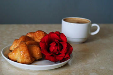 Cup of coffee, croissants and rose on table in room, romantic breakfast, Valentine Concept