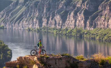 Young woman standing in mountain with bicycle above river
