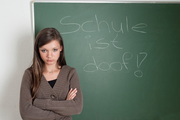 Junges Mädchen vor Schultafel mit dem Spruch 