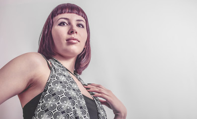Fashion portrait of gothic girl with short crimson hair and black-and-white dress on gray...