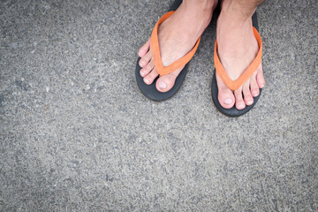Feet of a man wearing sandals on the old concrete floor.