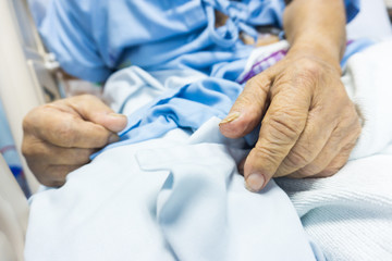Senior sickness hand on bed of hospital
