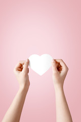 Hands holding white heart made of paper. Love and Valentine's day concept