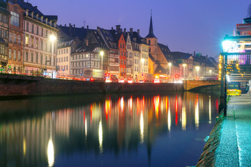 Obraz premium Picturesque quay and church of Saint Nicolas with mirror reflections in the river Ile during morning blue hour, Strasbourg, Alsace, France