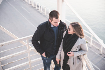 People in love theme. Attractive young couple enjoying in city outdoors. They standing on the city bridge, smiling and hugging.