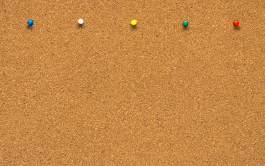 Group of thumbtacks pinned on corkboard