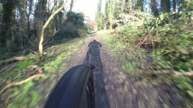 4K Wheel of a bike spinning as it speeds through a forest path - version 2