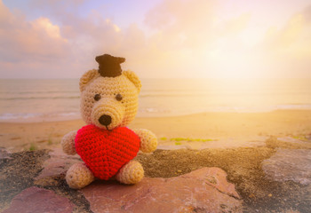 Teddy Bear with red heart sitting near the beach - vintage tone