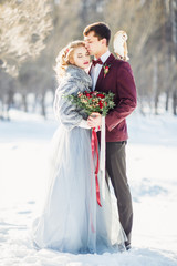The bride and groom in the winter outdoors. The owl sits on the shoulder of a man.