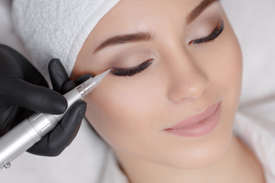 Cosmetologist making permanent make up at beauty salon