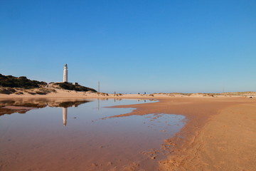 The lighthouse of the Cape of Trafalgar reflected in the water, in the coasts of the south of Spain