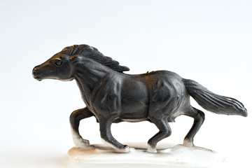 Black galloping plastic toy horse on a white background