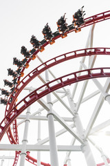 Roller coaster in the amusement park with people in a motion blu