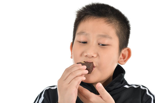 Portrait Of Asian Boy Eating Brownie Cake On White.