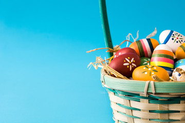 Colored easter eggs in a basket on blue background
