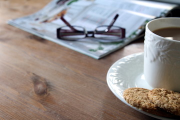Tea and biscuits or cookies, magazine and reading glasses on a w