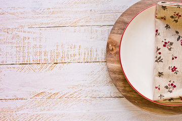 Off-white empty plate with red board on round cutting board, linen floral napkin, white plank wood background, Provence style, kitchen interior, minimalistic, kinfolk,flat lay