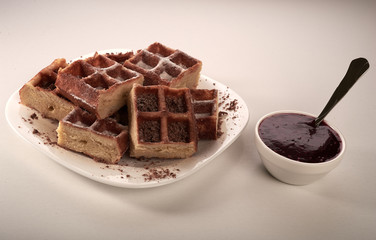 Belgian waffles with grated chocolate and icing on a white plate