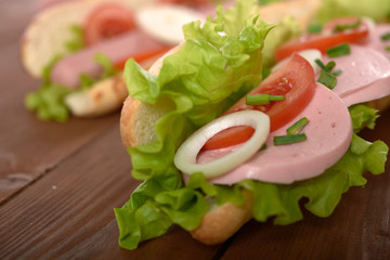 sandwich with sausage and vegetables on a wooden table