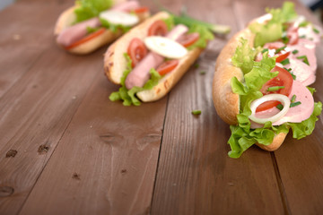 sandwich with sausage and vegetables on a wooden table