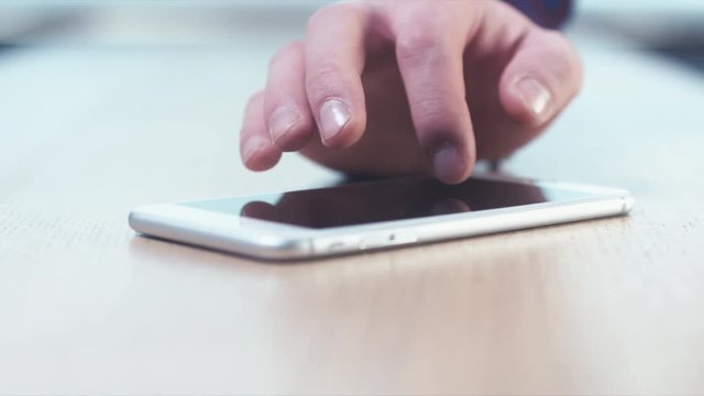 CU RL DOLLY Caucasian man using his phone on a wooden table, finger pointing screen. Selective focus. 4K UHD 60 FPS slow motion