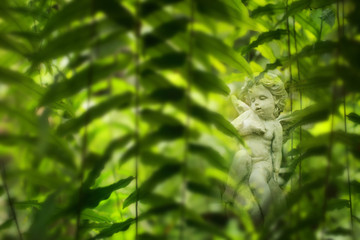Cupid sculpture in garden, background for Valentine's day. Selective focus and color toned.