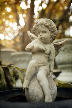 Cupid sculpture in garden, background for Valentine's day, color toned.