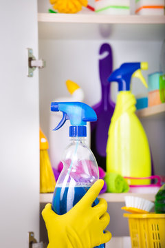 Woman putting spray bottle in pantry