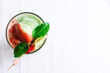 Topdown view of strawberry, banana, giwi smoothy glass with gree