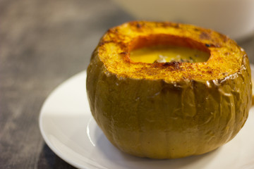 A delicious pumpkin soup in a pumpkin with nuts and toast bread.