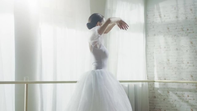 Young and Beautiful Ballerina Gracefully Dances on Her Pointe Ballet Shoes. She's Wearing White Tutu Dress. Studio is Sunny and Modern. In Slow Motion.  Shot on RED EPIC-W 8K Helium Cinema Camera.