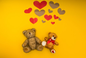 Two teddy bears on a yellow background and heart over them