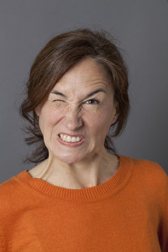 fun angry expression for winking middle aged woman showing teeth