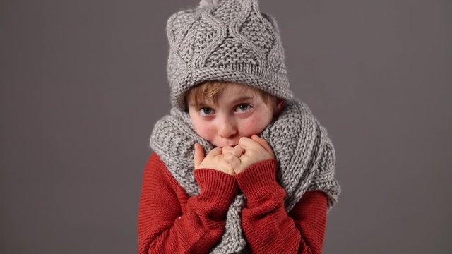unhappy little child protecting from cold with warm winter clothes