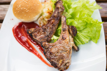 Grilled steak of lamb meat cut on slice with round bread, salad, oil, sauce and cup of orange juice