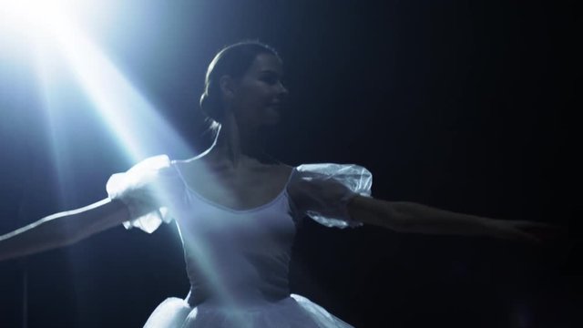  Mid Shot of a Beautiful Young Ballerina Dancing Gracefully in the Spotlight, Darkness Around Her. Shot on RED EPIC-W 8K Helium Cinema Camera.