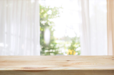 Wood table top on blur of curtain window and abstract green from garden background