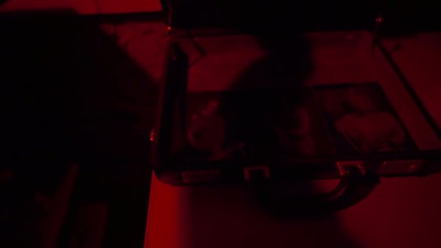 Man opens the suitcase in the darkroom close-up