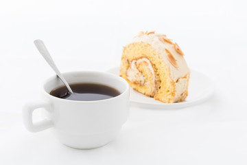 Almond roll cake on white dish with hot drink