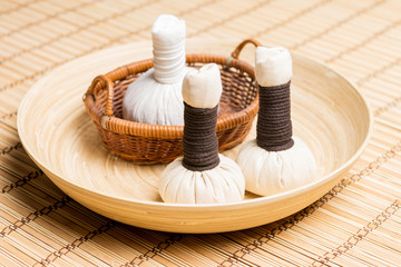 Fototapeta na wymiar Massage bundles on a plate on a bamboo mat