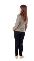 back view of standing young beautiful  woman in jeans.