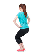 slim girl in sportswear is engaged in sports. She squats.