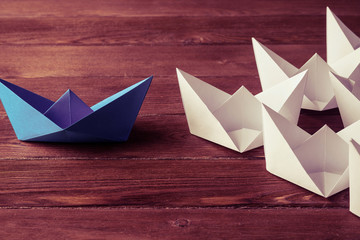 Business leadership concept with white and color paper boats on 