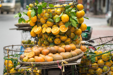 Full basket of orange fruit on vendor bike on Hanoi street, Vietnam