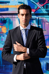 Young businessman wearing blue suit and tie in urban background