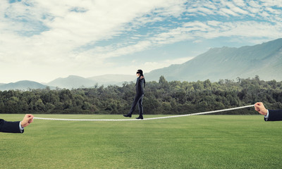 Business concept of risk support and assistance with man balancing on rope